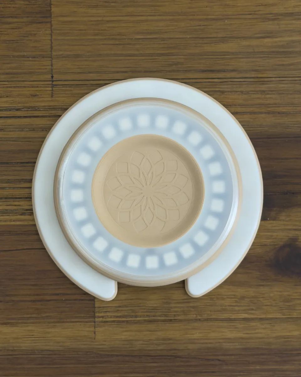 Top-down view of the Aura Light with the frosted cover on, its ring of LEDs softened into a diffuse band of light around the flower-engraved center
